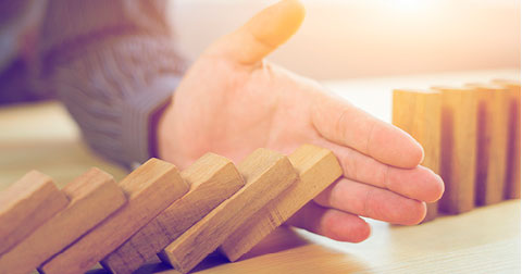 person stopping wooden blocks from falling over